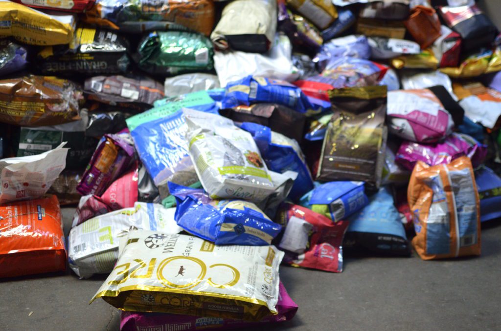 large pile of various bags of dog and cat kibble food