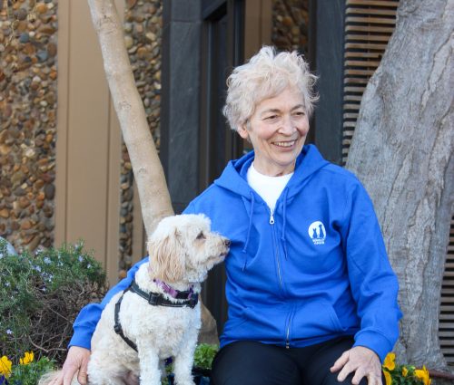 image of women wearing blue hoodie sitting next to fluffy dog